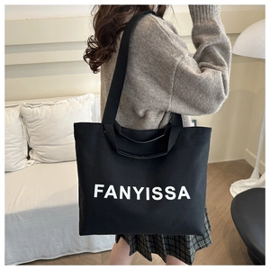 Minimalist black canvas tote bag with FANYISSA print shown worn over the shoulder