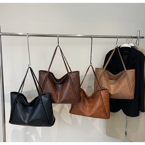 Detailed display of vintage tote bags in four colors hanging on a metal garment rack
