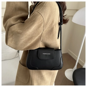 Close-up of a minimalist black leather underarm bag with Fashion & Bags logo detail
