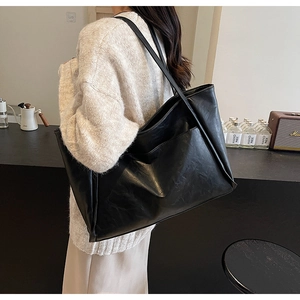 Macro detail of high-capacity black leather tote bag with fine texture and front pocket