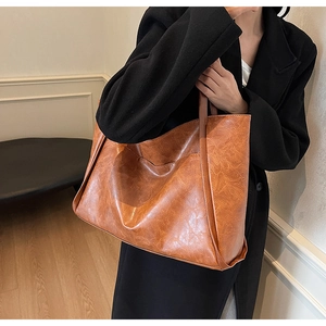 Brown vintage tote bag with textured synthetic leather shown over the shoulder on a model
