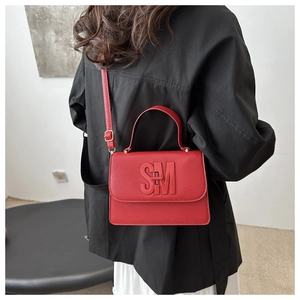 Détail du petit sac carré en cuir litchi rouge avec logo SM et bandoulière amovible