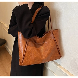 Detail of caramel brown tote bag with vintage texture and front pocket close-up