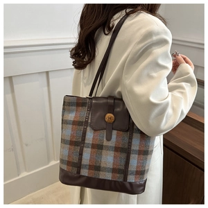 Detail of vintage plaid tote bag with brown faux leather trim and golden N logo button