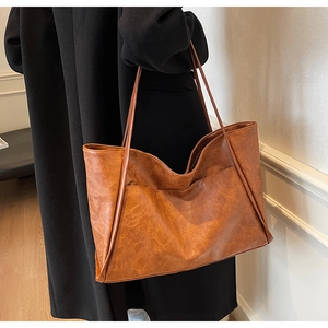 Detail of vintage brown tote bag texture and front pocket on a long black wool coat