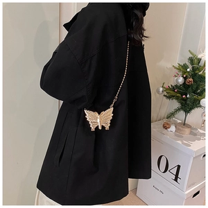Golden butterfly-shaped evening bag with a metal chain strap worn by a model