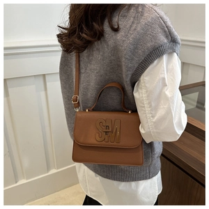 Détail du sac à main en cuir marron avec logo SM en métal et texture grainée