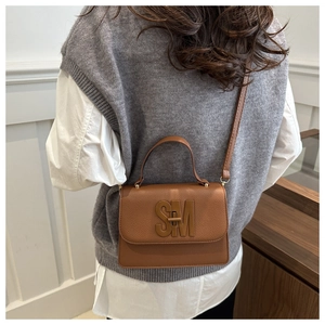 Sac en cuir grainé marron avec boucle SM porté en bandoulière pour un look chic