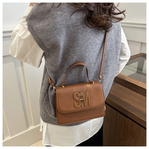 Gros plan d'un sac à main en cuir marron grainé avec un logo SM métallique chic