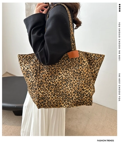 Detailed side view of leopard print tote bag with brown leather tag and canvas texture