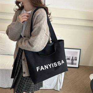 Minimalist black canvas lunch tote with white lettering shown in a cozy home setting
