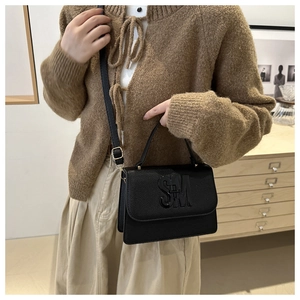 Détail d'un sac cabas en cuir grainé noir avec logo SM et bandoulière réglable mince