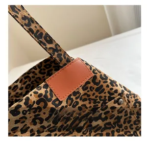 Close-up of leopard print fabric tote bag with brown leather trim and silver metal rivet