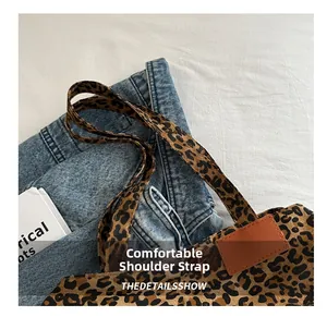 Detail view of leopard print canvas tote bag with orange leather patches and soft strap