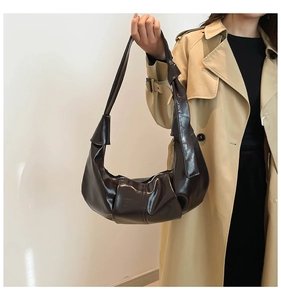 Detail of dark brown glossy croissant bag with knotted strap and half-moon structure