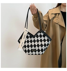 Detail of large tote bag featuring black and white diamond pattern and metal logo tag