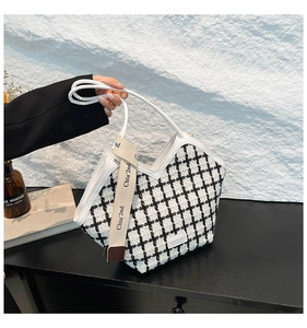Detail of black and white tweed tote bag with V-shaped opening and leather handles