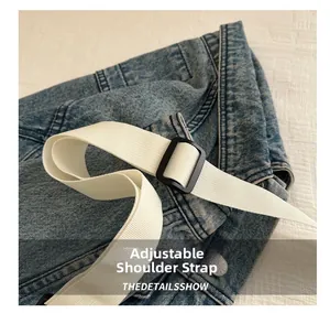 Detail eines verstellbaren weißen Webgurts an einer blauen Jeans-Tasche