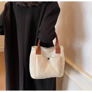 Détail du sac cabas en toile blanc cassé avec anse marron et poche avant boutonnée