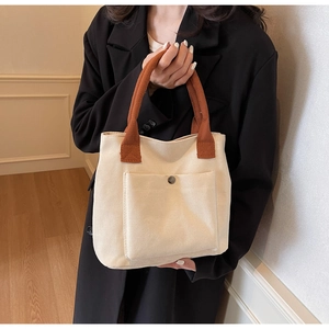 Canvas tote bag with brown handles and snap pocket shown on a model in a stylish setting