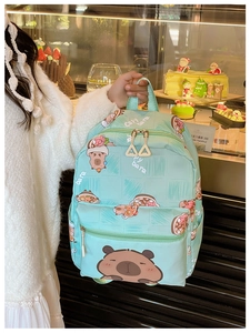 Close-up of mint green kids backpack featuring cute cartoon capybara prints and zipper