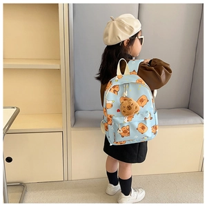 Detail eines blauen Kinderrucksacks mit Capybara-Mustern und kleinem Plüschtier-Anhänger