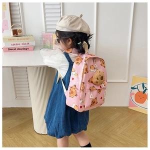 Detail eines rosa Cartoon-Rucksacks mit Plüschbären-Anhänger und süßen Tiermustern für Kinder