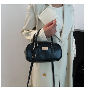 Detalle de bolso de mano negro elegante con cuero texturizado y detalles metálicos dorados