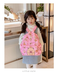 Pink cartoon capybara backpack for children shown being worn by a young girl