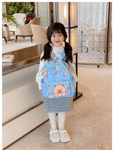 Toddler wearing a sky blue cartoon capybara backpack with side pockets in a bright room