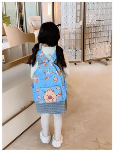 Blue kids' Capybara backpack shown on a child's back in a bright interior setting