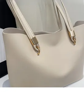 Dettaglio della borsa tote in pelle crema con eleganti fibbie metalliche rettangolari oro