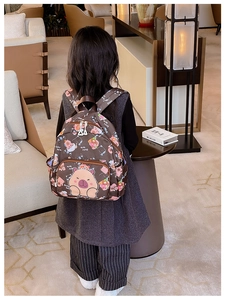 Rear view of a young girl wearing a dark brown cartoon capybara backpack for school