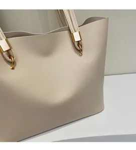 Dettaglio della borsa tote crema con anello in metallo dorato e attacco tracolla