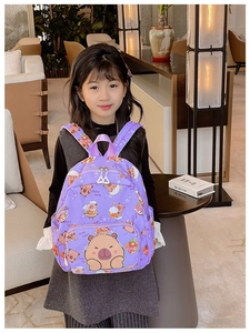 Close-up of cute purple capybara cartoon backpack worn by a child in a warm setting