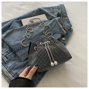 Détail du sac seau en strass avec cordon de serrage, perles et bandoulière chaîne