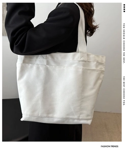 Detail view of large white canvas tote bag with multi-functional front pockets and straps