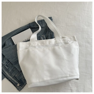 Detail view of white canvas tote bag with triple external pockets and durable handles