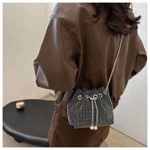 Détail du sac seau noir en strass avec fermeture à cordon et bandoulière chaîne