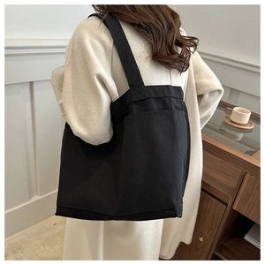 Rear view of a minimalist large black canvas tote bag being worn on the shoulder