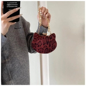 Close-up of leopard print cat-shaped handbag with jewel clasp and gold chain strap