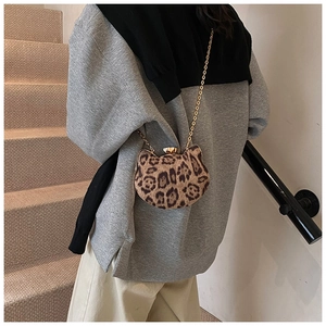 Detailed view of leopard print cat-ear crossbody bag with gold chain strap on shoulder
