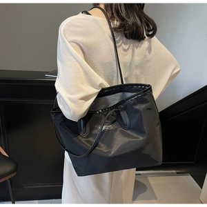 Detail of black tote bag showing smooth satin texture and fashion branding plate