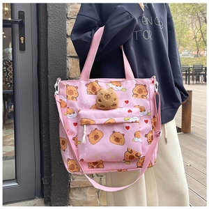 Pink canvas tote bag featuring cute cartoon capybara prints and a plush animal pendant