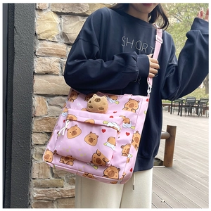Pink canvas crossbody bag featuring capybara patterns and a cute plush toy pendant detail
