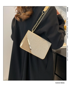 Detail of champagne gold sequin envelope bag with metal chain on a black coat