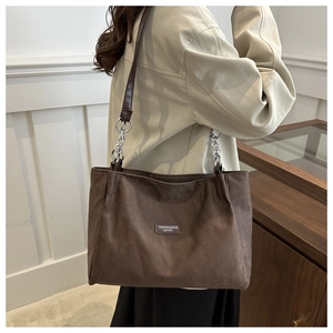 Detail of large brown suede tote bag with silver chain strap and fashion logo