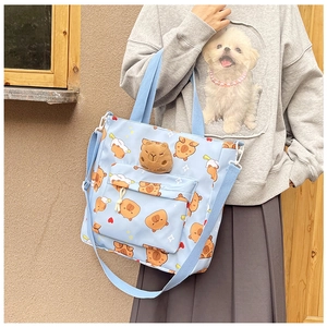 Detail of light blue canvas tote featuring cartoon capybara prints and 3D plush doll