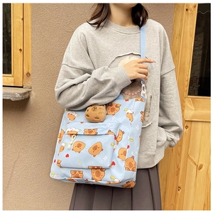Close-up of a blue canvas crossbody bag with brown cartoon capybara and cloud patterns