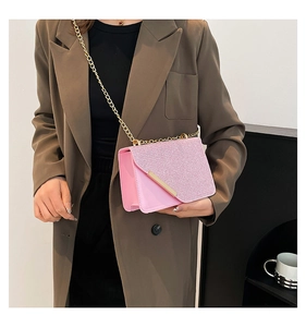 Detail of pink glitter crossbody bag with gold chain strap shown on a model